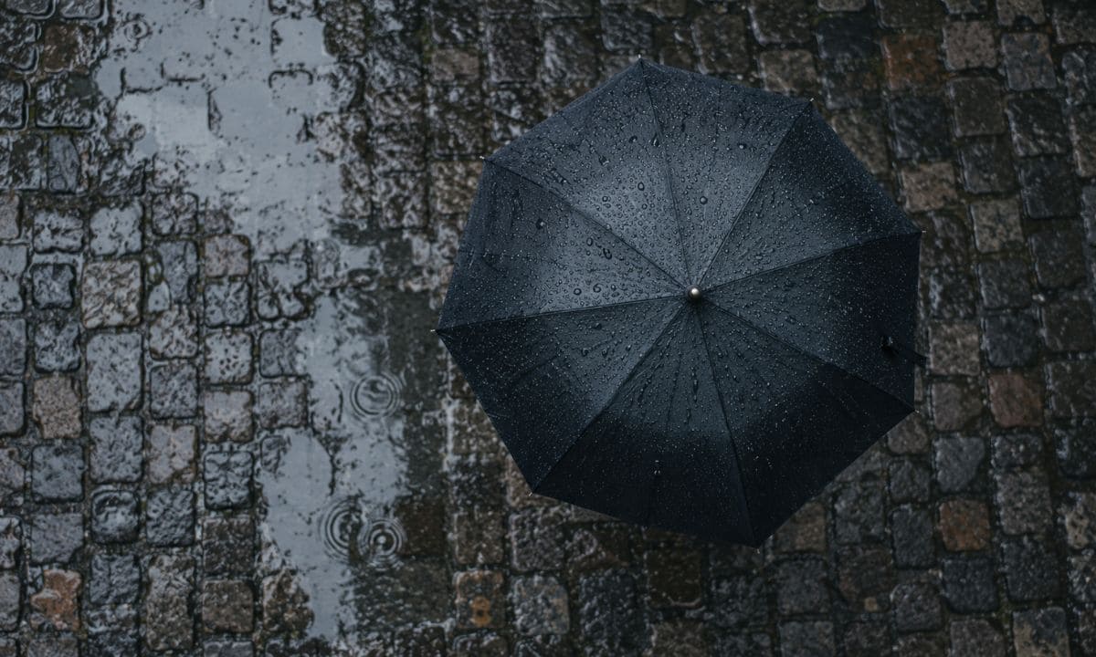 Single umbrella on cobblestone illustrating short rain captions for Instagram