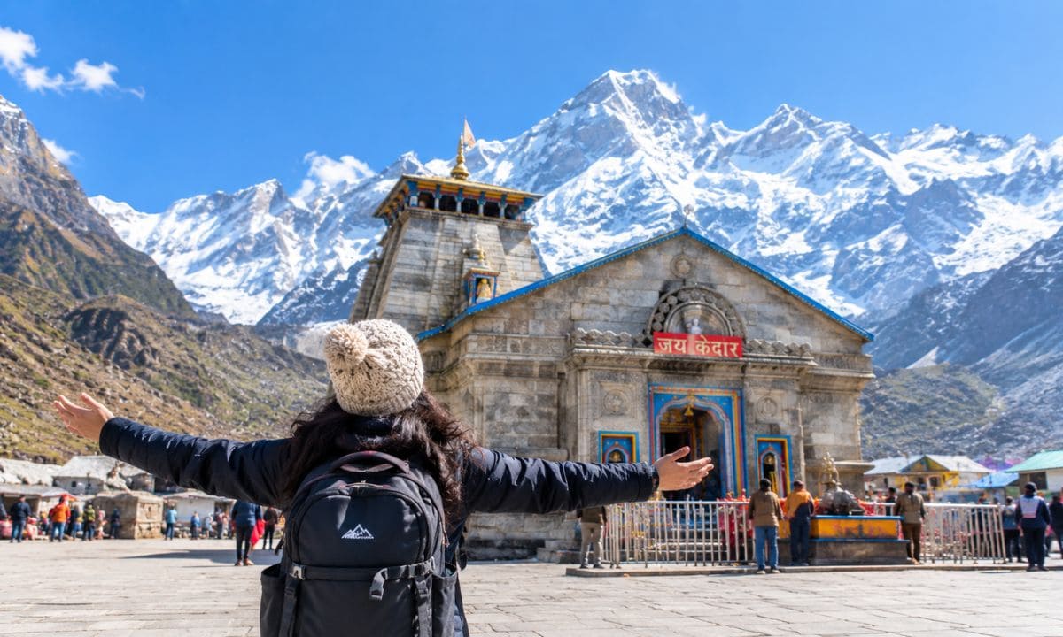 Traveler posing in front of Kedarnath temple with mountain backdrop